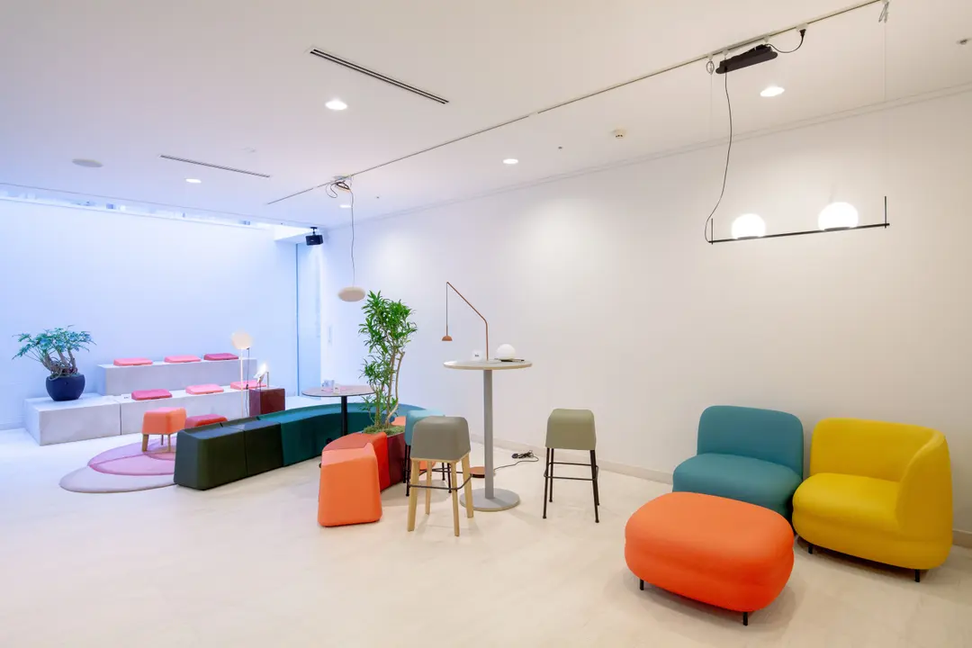Espacio blanco con sillones Vistas turquesa y amarillo y un puf naranja