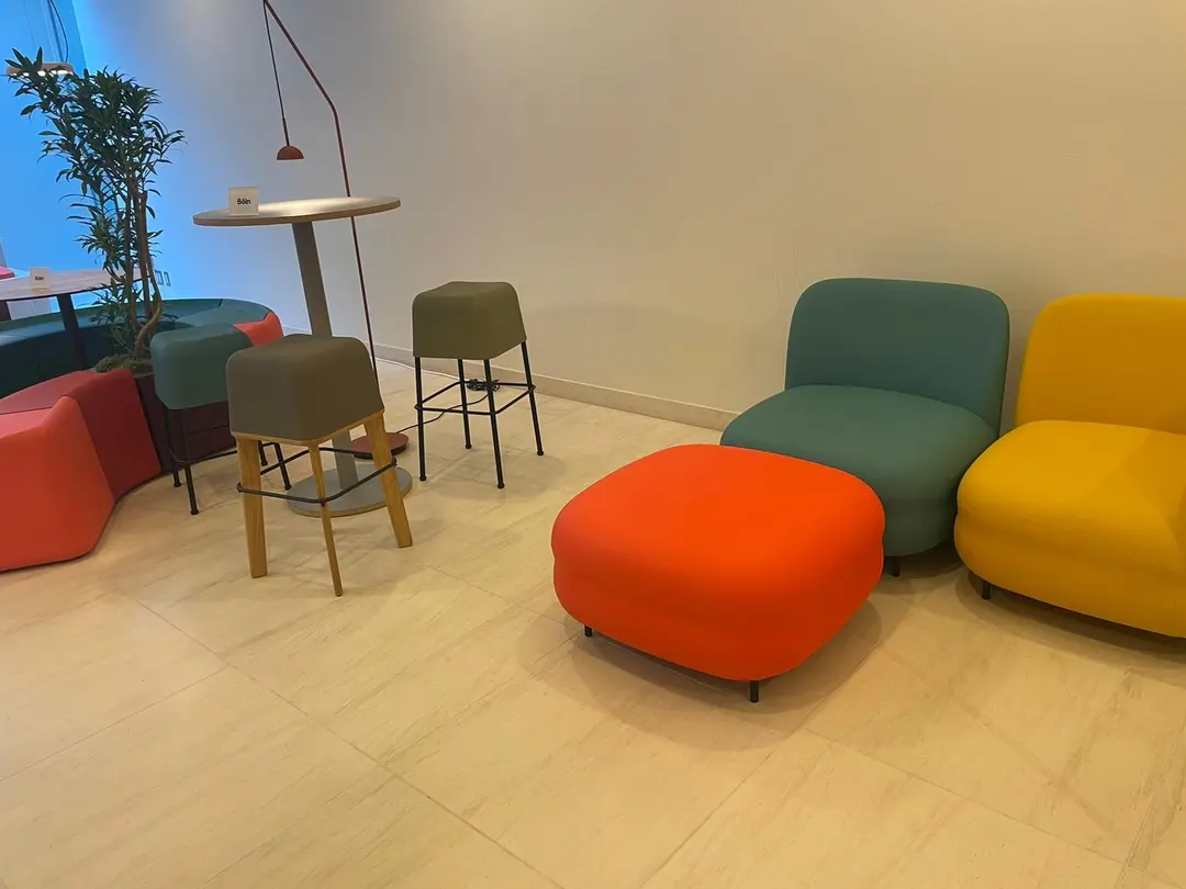 Zona de espera con sillones Vistas turquesa y amarillo y un puf naranja